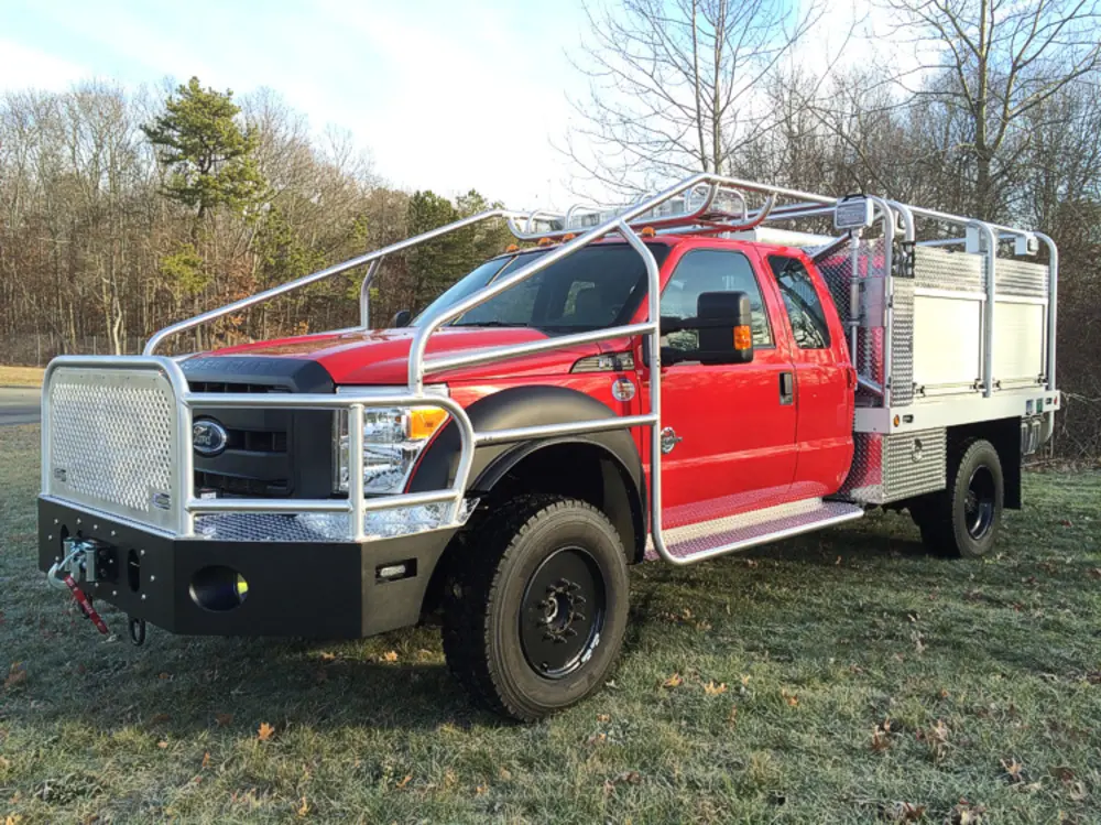 Exterior view of small fire truck showing cab, body compartments, and wheel/tire area.