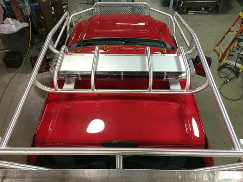Exterior view of small fire truck showing cab, body compartments, and wheel/tire area.