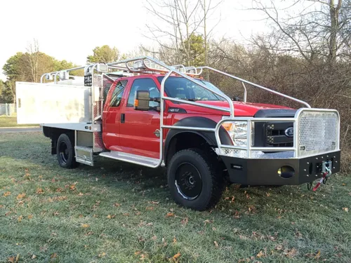 Exterior view of small fire truck showing cab, body compartments, and wheel/tire area.