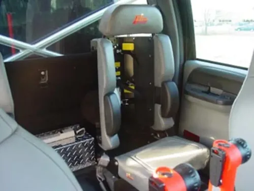 Exterior view of small fire truck showing cab, body compartments, and wheel/tire area.