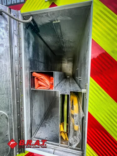 Inside narrow rear compartment with orange hose and shelf cubby.