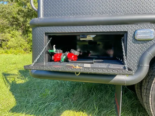 Open rear side compartment containing small red fittings.