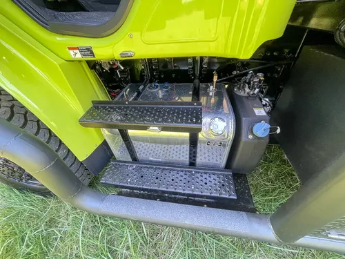 Battery and cylinder hardware mounted behind cab step.