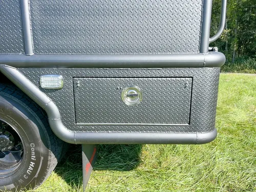 Closed lower compartment near rear wheel and mudflap.