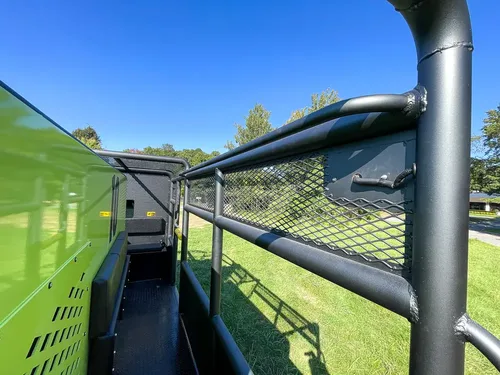 Narrow side walkway beside tank with cage rail overhead.