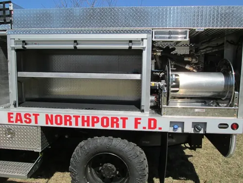 Exterior view of small fire truck showing cab, body compartments, and wheel/tire area.