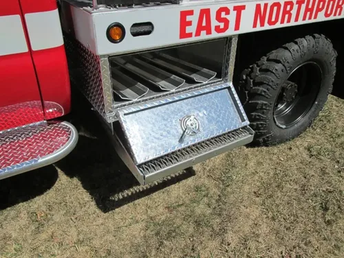 Exterior view of small fire truck showing cab, body compartments, and wheel/tire area.