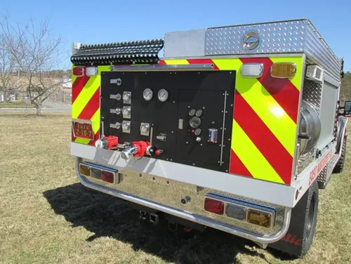 Exterior view of small fire truck showing cab, body compartments, and wheel/tire area.