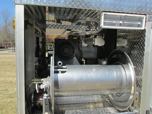 Exterior view of small fire truck showing cab, body compartments, and wheel/tire area.