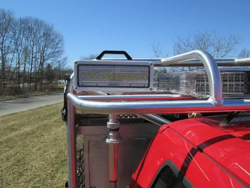 Exterior view of small fire truck showing cab, body compartments, and wheel/tire area.