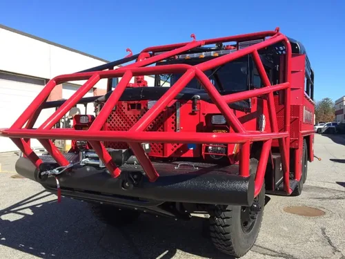 Exterior view of small fire truck showing cab, body compartments, and wheel/tire area.