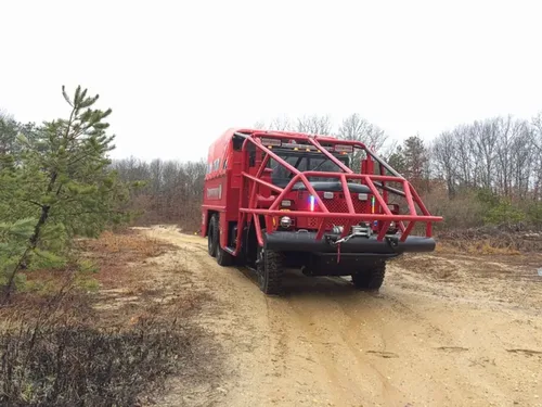 Exterior view of small fire truck showing cab, body compartments, and wheel/tire area.