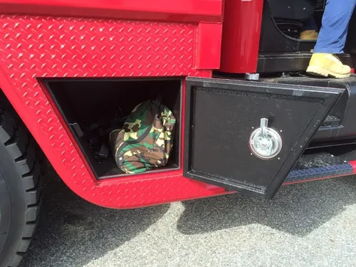 Exterior view of small fire truck showing cab, body compartments, and wheel/tire area.