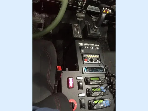Exterior view of small fire truck showing cab, body compartments, and wheel/tire area.