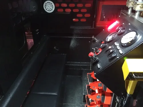 Exterior view of small fire truck showing cab, body compartments, and wheel/tire area.