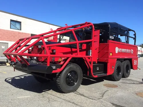 Exterior view of small fire truck showing cab, body compartments, and wheel/tire area.