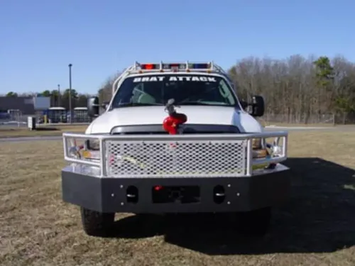 Exterior view of small fire truck showing cab, body compartments, and wheel/tire area.