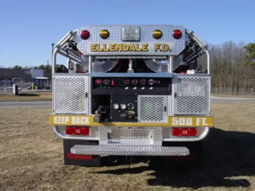 Exterior view of small fire truck showing cab, body compartments, and wheel/tire area.