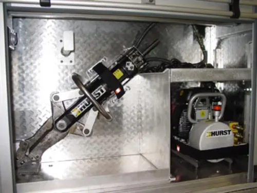 Exterior view of small fire truck showing cab, body compartments, and wheel/tire area.