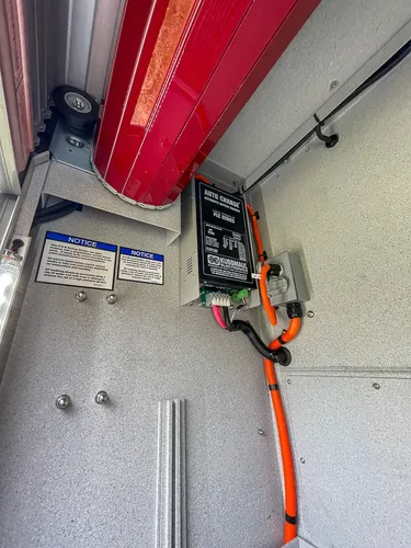 Compartment wall close-up with battery charger and labels.