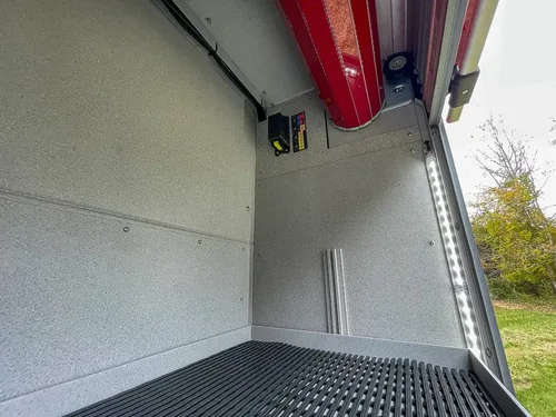 Long compartment interior showing overhead strip light and shelf rails.
