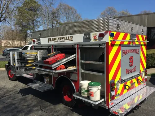 Exterior view of small fire truck showing cab, body compartments, and wheel/tire area.