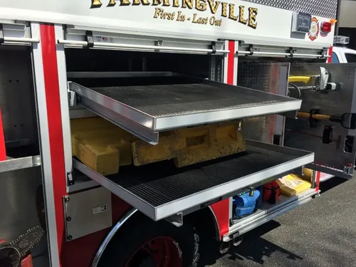 Exterior view of small fire truck showing cab, body compartments, and wheel/tire area.