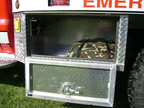 Exterior view of small fire truck showing cab, body compartments, and wheel/tire area.