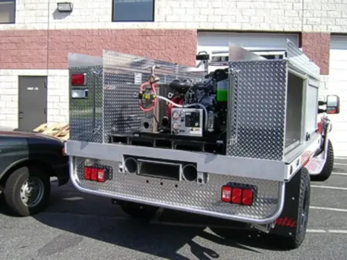 Exterior view of small fire truck showing cab, body compartments, and wheel/tire area.