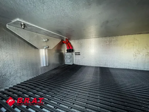 Empty aluminum compartment with black ribbed floor mat.