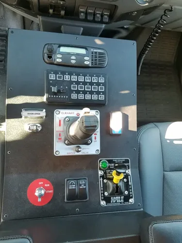 Exterior view of small fire truck showing cab, body compartments, and wheel/tire area.