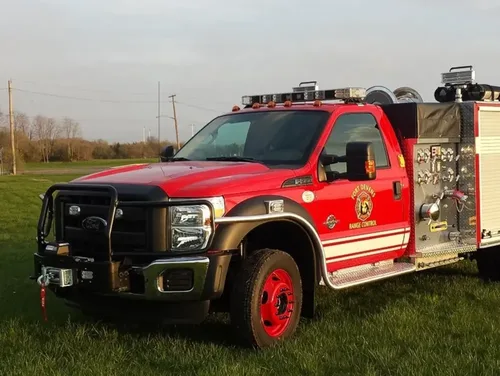 Exterior view of small fire truck showing cab, body compartments, and wheel/tire area.