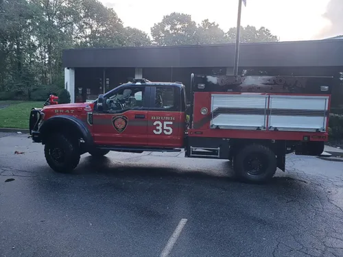 Exterior view of small fire truck showing cab, body compartments, and wheel/tire area.