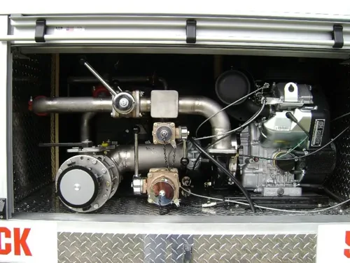 Exterior view of small fire truck showing cab, body compartments, and wheel/tire area.
