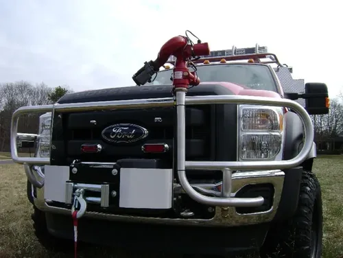 Exterior view of small fire truck showing cab, body compartments, and wheel/tire area.