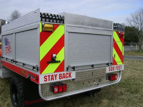 Exterior view of small fire truck showing cab, body compartments, and wheel/tire area.