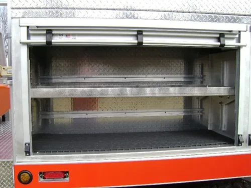Exterior view of small fire truck showing cab, body compartments, and wheel/tire area.
