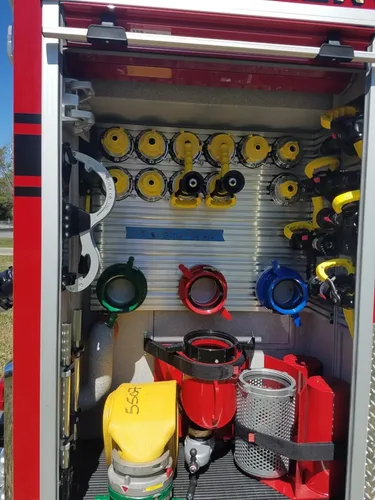 Exterior view of small fire truck showing cab, body compartments, and wheel/tire area.