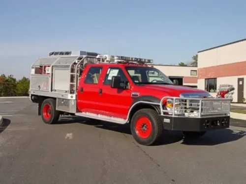 Exterior view of small fire truck showing cab, body compartments, and wheel/tire area.