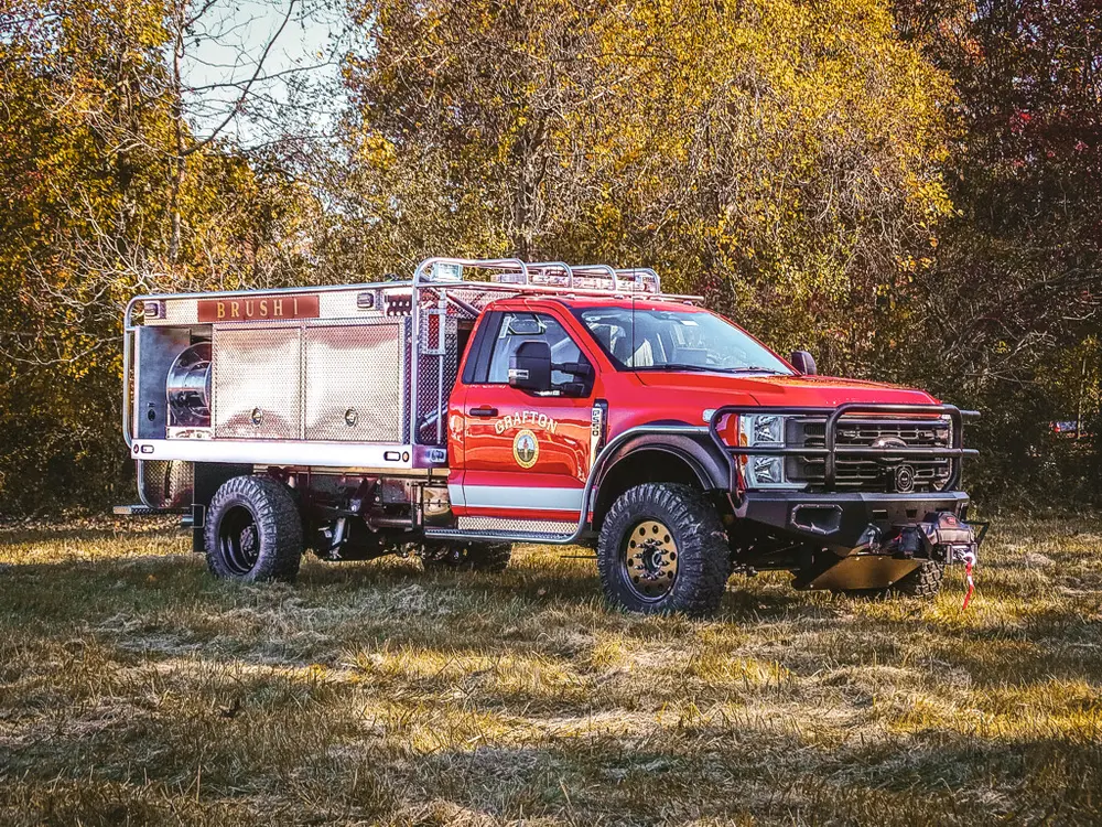 Front-left three-quarter exterior view of red brush truck with utility body.