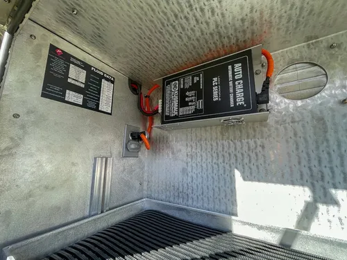 Side compartment interior with mounted charger and warning label.