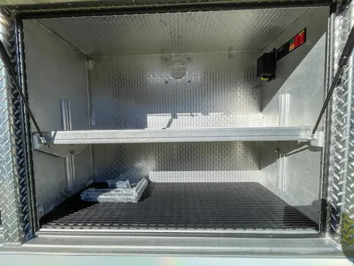 Open side compartment with two shelves and small items on floor.