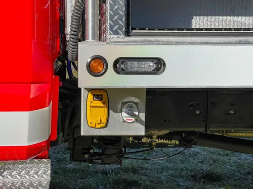 Rear corner underbody close-up with marker light and connector panel.