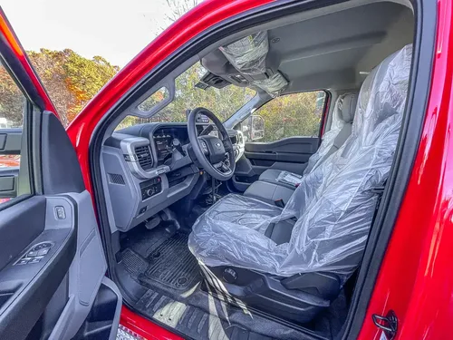 Open driver door view showing front seats with protective covers.