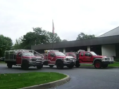 Exterior view of small fire truck showing cab, body compartments, and wheel/tire area.