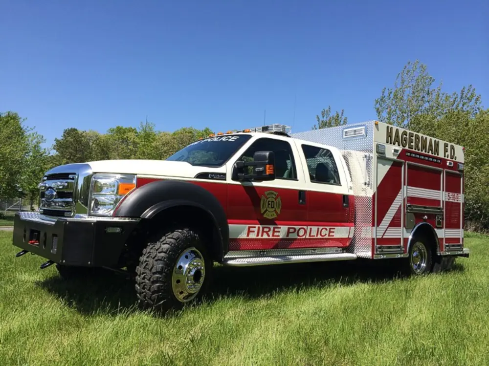 Exterior view of small fire truck showing cab, body compartments, and wheel/tire area.