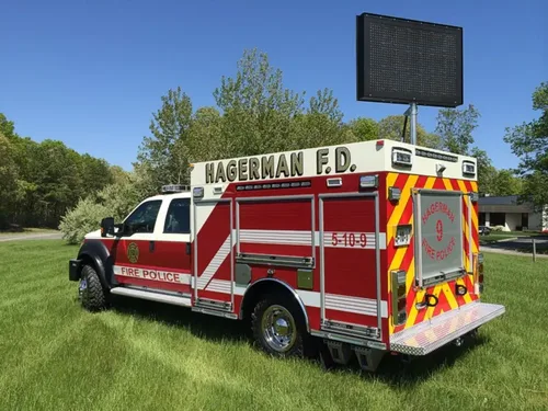 Exterior view of small fire truck showing cab, body compartments, and wheel/tire area.
