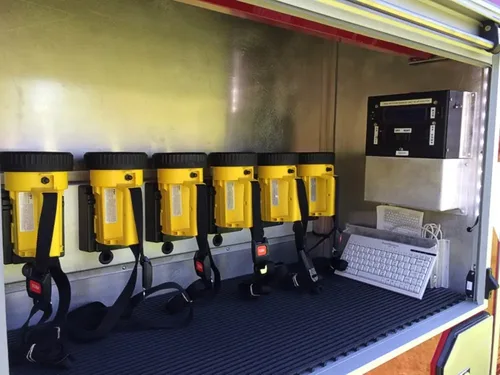 Exterior view of small fire truck showing cab, body compartments, and wheel/tire area.