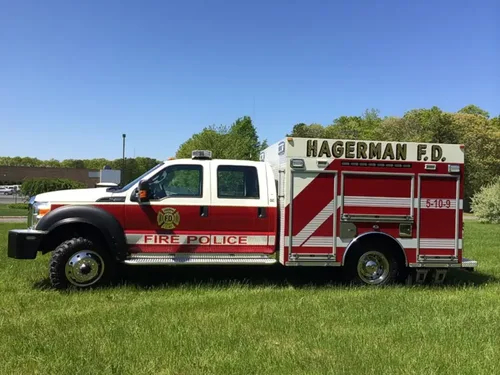 Exterior view of small fire truck showing cab, body compartments, and wheel/tire area.