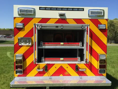 Exterior view of small fire truck showing cab, body compartments, and wheel/tire area.